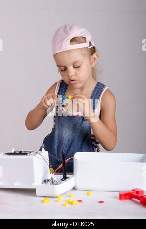 Girl playing in the repairer and repairs toy microwave. Girl Wrench twist the screw nut Stock Photo