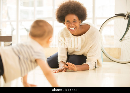 Mother and baby son playing on living room floor Stock Photo