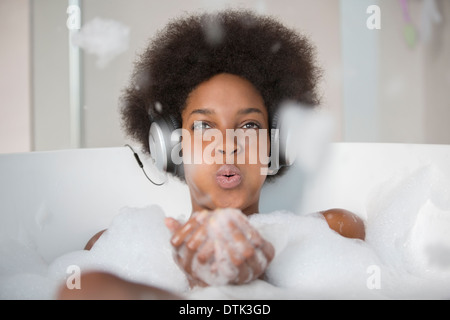 Woman listening to headphones in bath Stock Photo