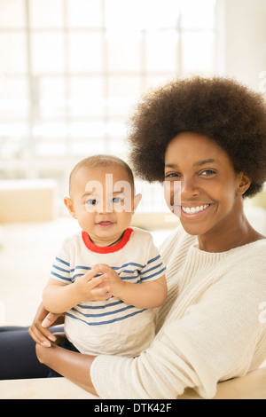 Mother holding baby boy on sofa Stock Photo