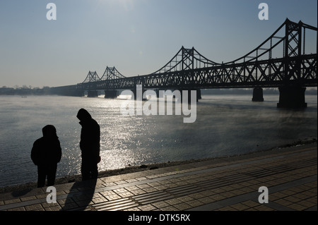 Two men standing on the Yalu River front near the Sino-Korean Friendship Bridge .  Liaoning province. Dandong, China. Stock Photo