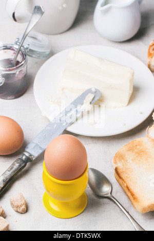 Breakfast with eggs and toast served with jam and butter on a white table cloth Stock Photo