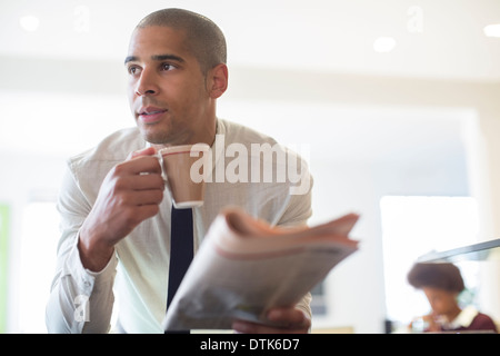 Businessman reading newspaper and drinking coffee Stock Photo