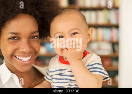 Closeup of mother hands holding cute tiny baby feet, showing baby foot.  Pink Background. Horizontal. Stock Photo