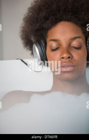 Woman listening to headphones in bath Stock Photo