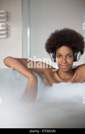 Woman listening to headphones in bath Stock Photo