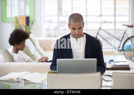 Man using laptop at desk in living room Stock Photo