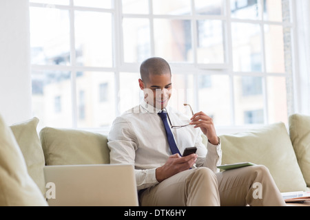 Businessman using cell phone on sofa Stock Photo