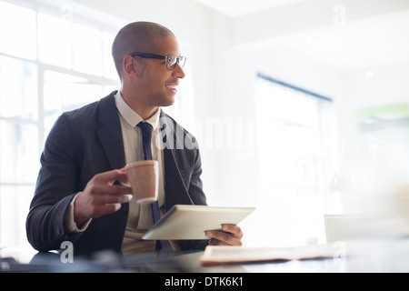 Businessman using digital tablet and drinking coffee Stock Photo