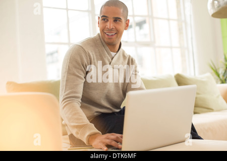 Man using laptop on sofa Stock Photo