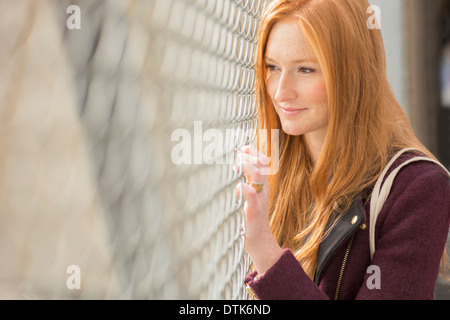 Woman peering through chain link fence Stock Photo