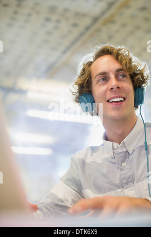 Businessman listening to headphones in office Stock Photo