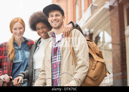 Friends smiling together on city street Stock Photo