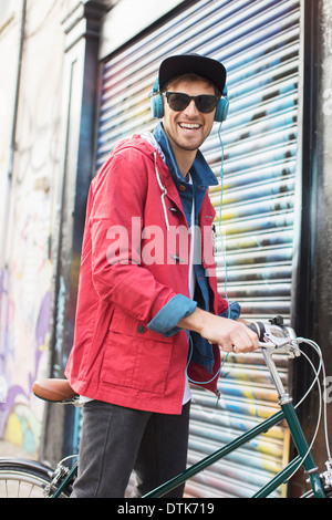 Man pushing bicycle on city street Stock Photo