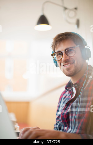 Man wearing headphones and using laptop Stock Photo