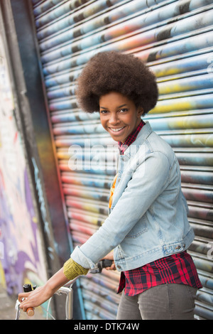 Woman with bicycle in front of graffiti wall Stock Photo