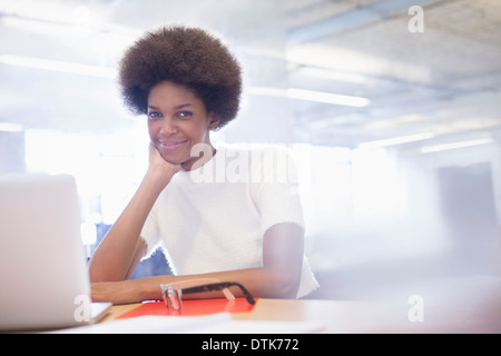 Businesswoman smiling at desk in office Stock Photo