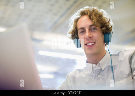 Businessman listening to headphones in office Stock Photo