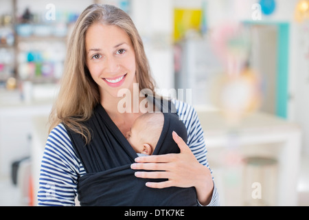 Mother holding sleeping baby boy in sling Stock Photo