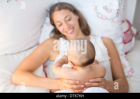 Mother holding baby boy on bed Stock Photo