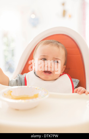 Baby boy crying in high chair Stock Photo