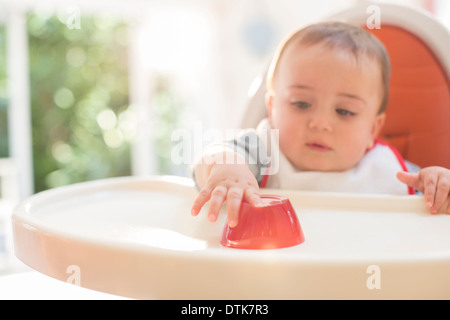 Baby boy eating in high chair Stock Photo