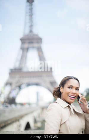 Woman talking on cell phone by Eiffel Tower, Paris, France