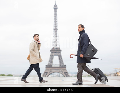 Businessmen walking past Eiffel Tower, Paris, France Stock Photo