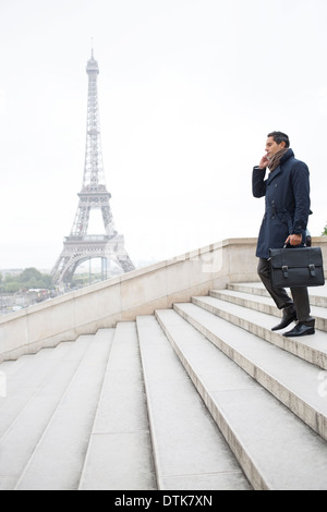 Businessman talking on cell phone on steps near Eiffel Tower, Paris, France Stock Photo