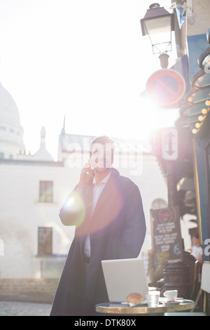 Businessman talking on cell phone at sidewalk cafe Stock Photo