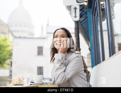 Businesswoman on cell phone at sidewalk cafe near Sacre Coeur Basilica, Paris, France Stock Photo