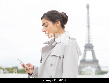 Businesswoman using cell phone near Eiffel Tower, Paris, France Stock Photo