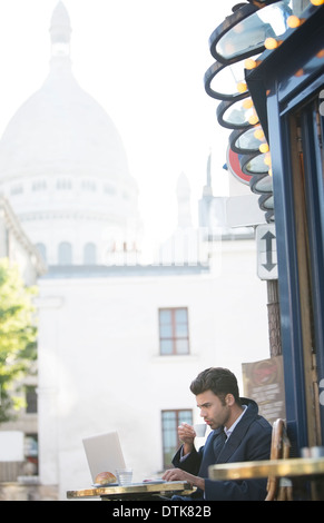 Businessman working at sidewalk cafe near Sacre Coeur Basilica, Paris, France Stock Photo