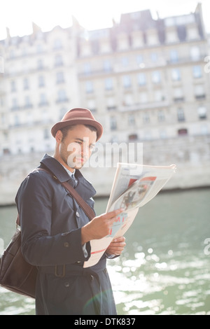 Businessman reading newspaper along Seine River, Paris, France Stock Photo