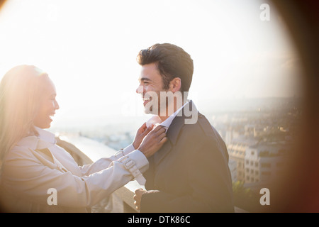 Woman holding boyfriend's collar on urban balcony Stock Photo
