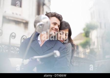 Couple sitting on scooter in city Stock Photo