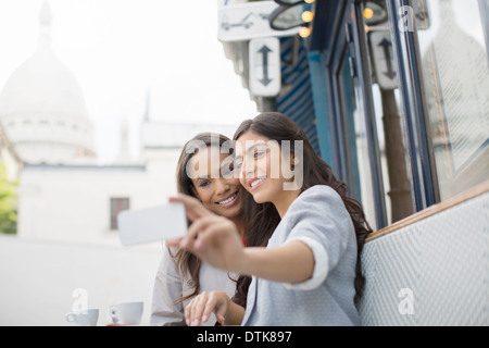 Friends taking self-portrait at sidewalk cafe near Sacre Coeur Basilica, Paris, France Stock Photo