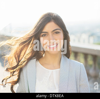 Wind blowing long hair of woman smiling outdoors Stock Photo
