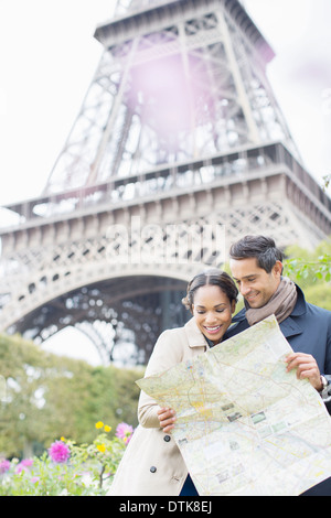 Couple reading map in front of Eiffel Tower, Paris, France