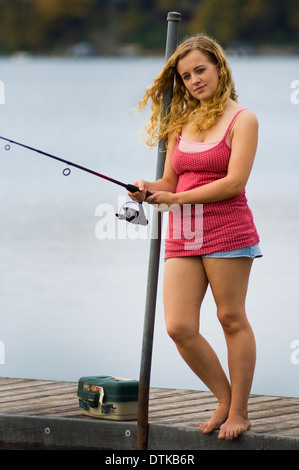 A young woman fishing on a dock Stock Photo - Alamy