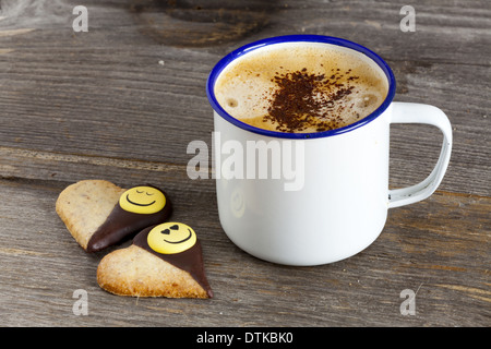 Enamel Mugs with hot Coffee and two Cookies with Heart Shape on old rustic wooden board with and Copy Space on left Image Area Stock Photo