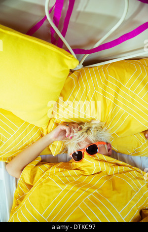 Woman wearing sunglasses in bed