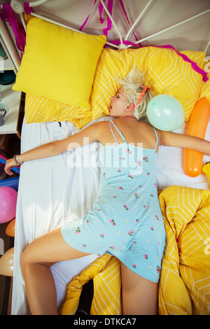 Woman sleeping on bed after party Stock Photo