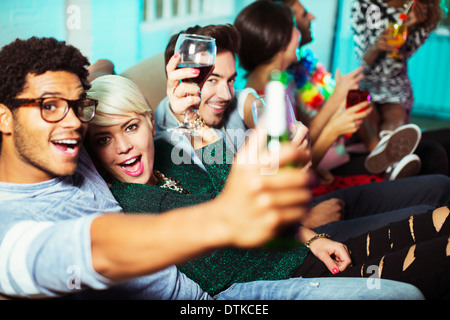 Friends drinking on sofa at party Stock Photo