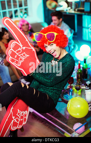Woman wearing wig, oversized sunglasses and foam finger Stock Photo
