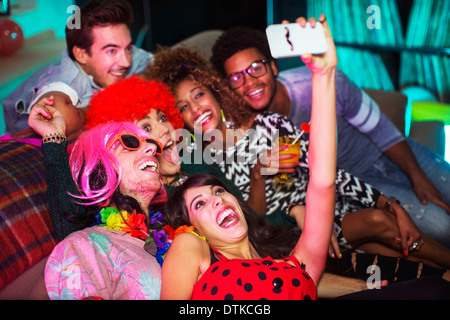 Friends taking pictures on sofa at party Stock Photo