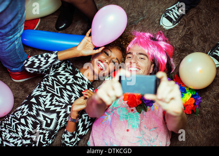 Couple taking self-portrait with cell phone on floor at party