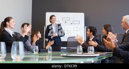 Business people applauding colleague in meeting Stock Photo