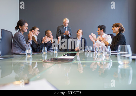 Business people applauding colleague in meeting Stock Photo