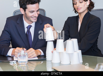 Business people stacking cups in meeting Stock Photo